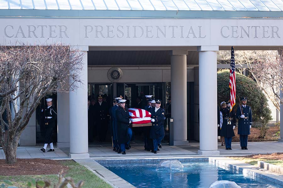 Military personnel carry President Carter's casket