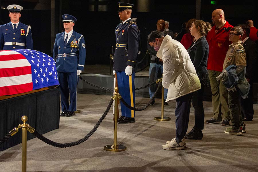 A mourner bows toward the casket.