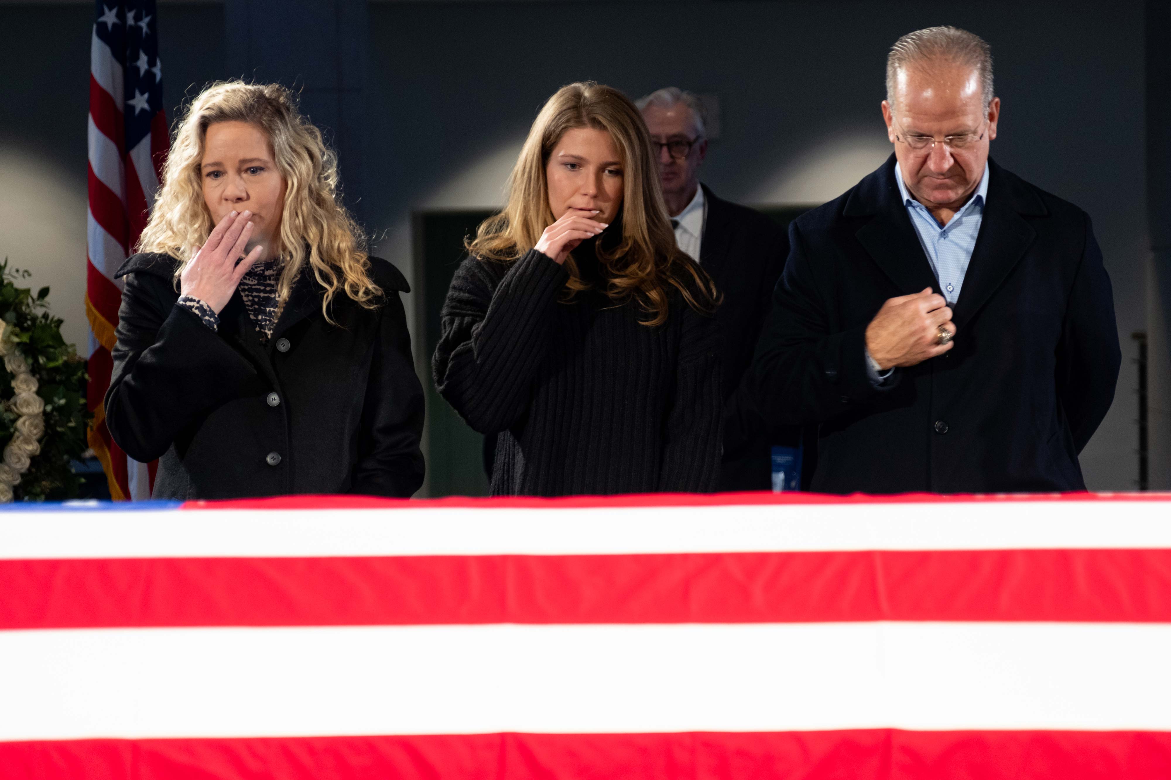 Mourners stand beside casket.